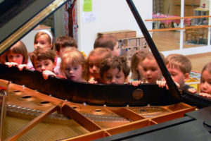 Preschoolers looking inside a piano.