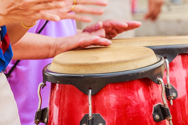 Hands drumming on a conga drum.