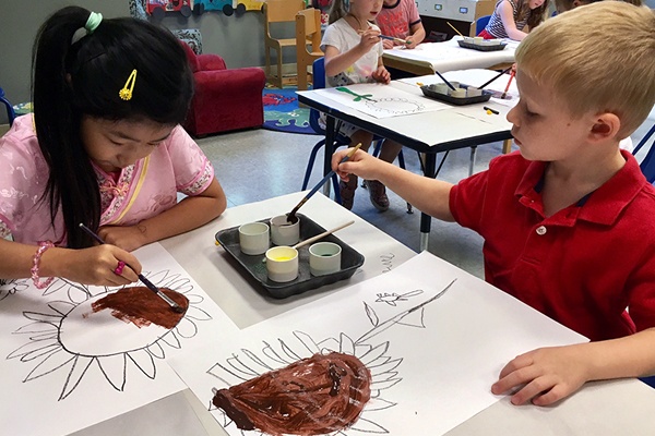 Young children painting in a class.