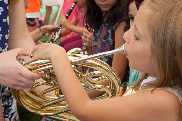 young child being shown how to play the French horn